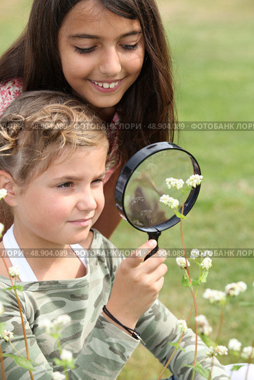 Girls looking through magnifying glass. Стоковое фото, агентство Ingram Publishing / Фотобанк Лори