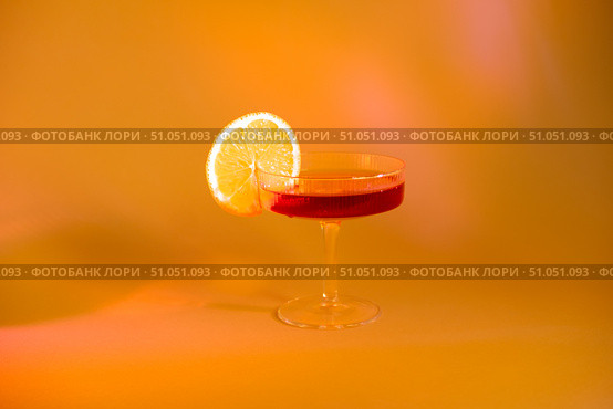 Glass of champagne with a slice of orange on an orange background, with shadows. Стоковое фото, фотограф Кашапова Эльвира / Фотобанк Лори