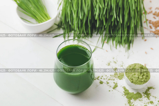 Glass with fresh wheatgrass juice and powder on light background. Стоковое фото, фотограф Pixel_shot / Фотобанк Лори