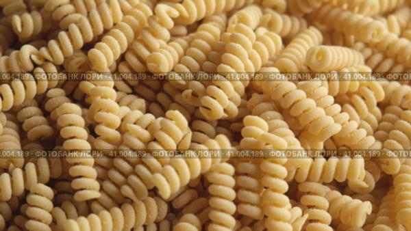 Gluten Free Cornmeal Pasta Wallpaper. Spiral Raw Macaroni from Corn and Rice flour rotating on Turntable. Close Up Top View. Uncooked Pasta Spinning. Full Frame. Food Background. Fusilli Bucati Corti. Стоковое видео, видеограф Марина Демидюк / Фотобанк Лори