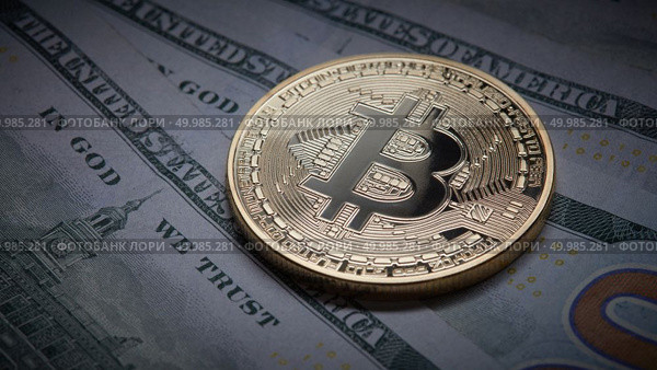Golden bitcoin coins on a paper dollars money. Virtual Crypto currency. New virtual money Dollars money. Concept of shadow economy. Coin bitcoin on the background of a pile of dollar bills as underground economy. Стоковое фото, агентство Ingram Publishing / Фотобанк Лори