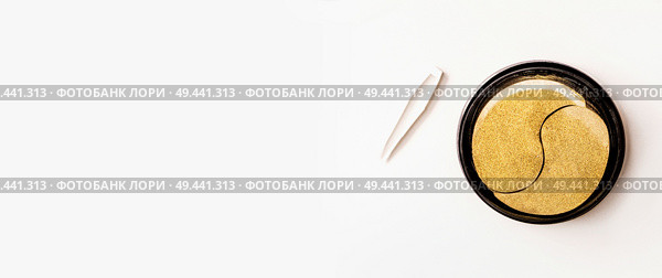 Golden eye patches in jar with tweezers. Hydrogel patch.  Anti aging and lifting . Face skin care. Hydrating and wrinkles patch. Modern facial cosmetic concept.Top view with copy space. Стоковое фото, агентство Ingram Publishing / Фотобанк Лори