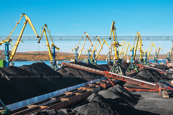 Горы угля в морском порту, грузовые вагоны из под угля, телескопические ленточные транспортеры, которые перераспределяют уголь по участку. Стоковое фото, фотограф Павел Просянов / Фотобанк Лори