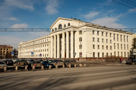 Государственная краевая универсальная научная библиотека с парковкой автомобилей напротив на улице Карла Маркса, 114, в весенний солнечный день.Красноярск. Россия. (2021 год). Редакционное фото, фотограф Светлана Попова / Фотобанк Лори