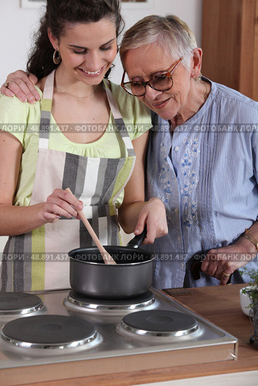 Granddaughter cooking for her grandmother. Стоковое фото, агентство Ingram Publishing / Фотобанк Лори