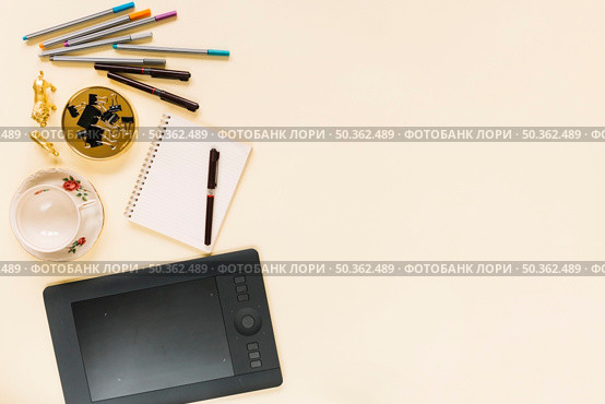 graphic digital tablet with felt tip pen spiral notebook empty ceramic cup cream background. Стоковое фото, агентство Ingram Publishing / Фотобанк Лори