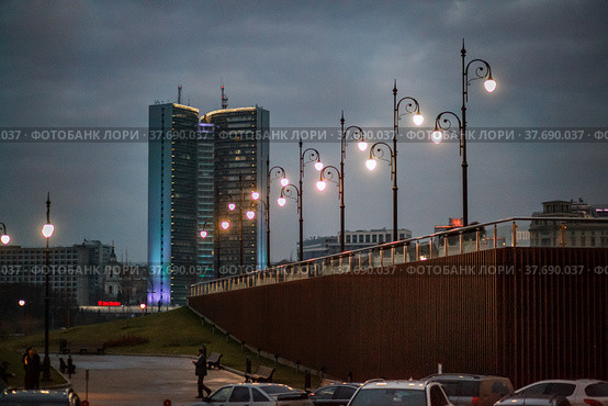 Grey soviet constructivist building with evening illumination and street lightings. Grey cloudy sky at sunset or dusk. Moscow (2014 год). Редакционное фото, фотограф Alexey Rezvykh / Фотобанк Лори
