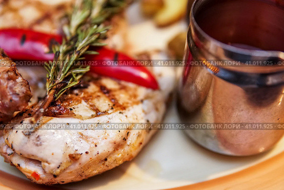 Grilled chicken, baked with potatoes and chili pepper. Food is served on a platter with tomato sauce and decorated with rosemary branch. Курица-гриль, запеченная с картофелем и перцем чили. Блюдо подается на блюде с томатным соусом и украшается веточкой розмарина. Стоковое фото, фотограф Дмитрий Березнев / Фотобанк Лори