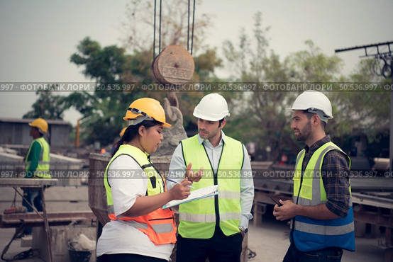 Group of architects, construction foremen, and construction engineers review the work and talk about how the project, in the construction site. Стоковое фото, агентство Ingram Publishing / Фотобанк Лори