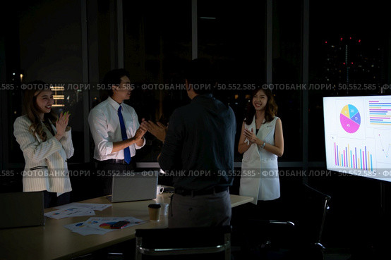 Group of broker international stock traders working actively at night in office, Everyone is congratulating the team on their success. Стоковое фото, агентство Ingram Publishing / Фотобанк Лори