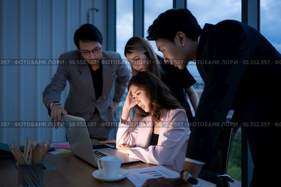 Group of broker international stock traders working actively at night in office, A young woman is working hustle to present a client with friends helping her with information. Стоковое фото, агентство Ingram Publishing / Фотобанк Лори