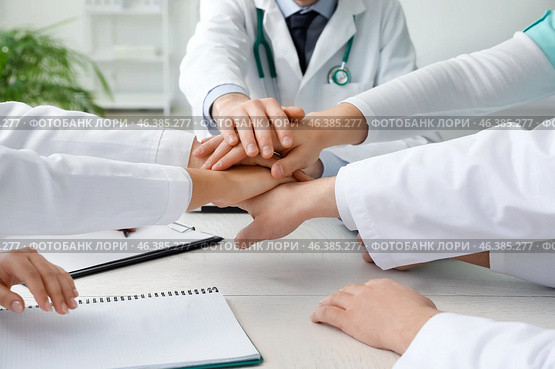 Group of doctors putting hands together in clinic. Стоковое фото, фотограф Pixel_shot / Фотобанк Лори