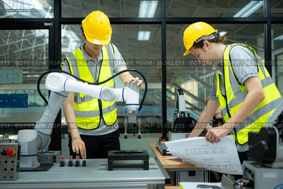 Group of engineers and technicians learning the technology to control hand robots for industrial usage. Стоковое фото, агентство Ingram Publishing / Фотобанк Лори