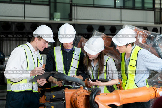 Group of engineers and technicians working together in a robotic arm factory. Inspecting robot arm before delivering to customers. Стоковое фото, агентство Ingram Publishing / Фотобанк Лори