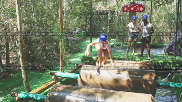 Group of excited people passing water obstacle course at adventure park. Стоковое видео, видеограф Яков Филимонов / Фотобанк Лори
