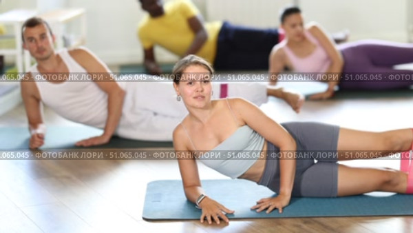 Group of multinational people training leg muscles using resistance bands during Pilates class. Стоковое видео, видеограф Яков Филимонов / Фотобанк Лори