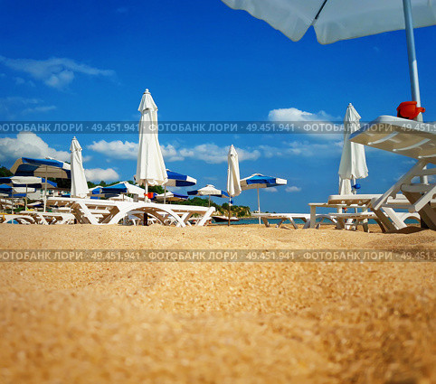 Group of sunbeds and umbrellas in the beach near the sea. Summer vacation background. Стоковое фото, агентство Ingram Publishing / Фотобанк Лори