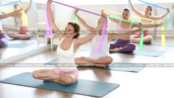 Group Pilates classes - woman doing body stretching using elastic bands. Стоковое видео, видеограф Яков Филимонов / Фотобанк Лори