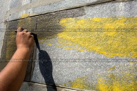 Грунтовка, стены перед покраской, подготовительные работы. Man's hand is brushing along the wall. Rough wall finishing. Стоковое фото, фотограф Iva Noel / Фотобанк Лори