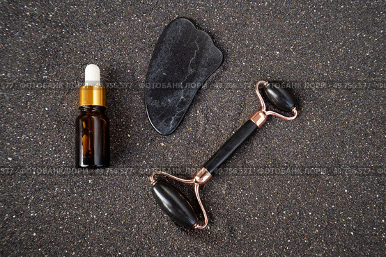 gua sha, face massage roller made of natural stone over black sand background. gua sha, face massage roller. Стоковое фото, агентство Ingram Publishing / Фотобанк Лори