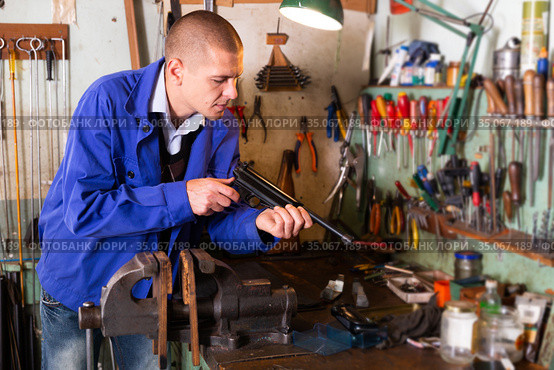 Gunsmith assembling smallbore sporting pistol in workshop. Стоковое фото, фотограф Яков Филимонов / Фотобанк Лори