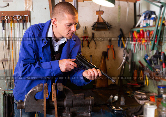 Gunsmith disassembles and repairs pistol in weapons workshop. Стоковое фото, фотограф Яков Филимонов / Фотобанк Лори