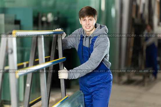 Guy glazer employee in blue overall works in glass processing shop. Стоковое фото, фотограф Яков Филимонов / Фотобанк Лори