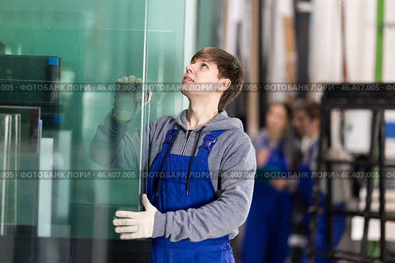 Guy glazer employee in blue overall works in glass processing shop. Стоковое фото, фотограф Яков Филимонов / Фотобанк Лори