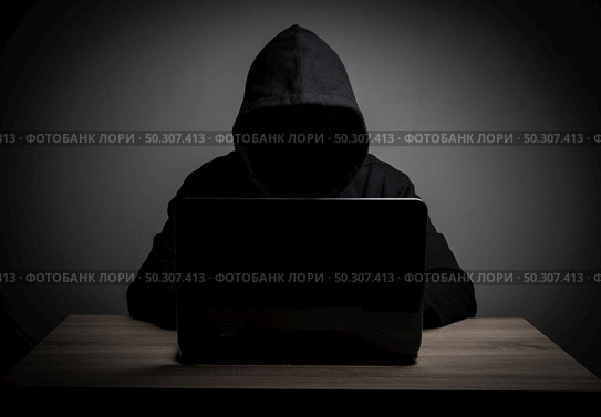 Hacker work front of his laptop computer with dark face. Стоковое фото, агентство Ingram Publishing / Фотобанк Лори