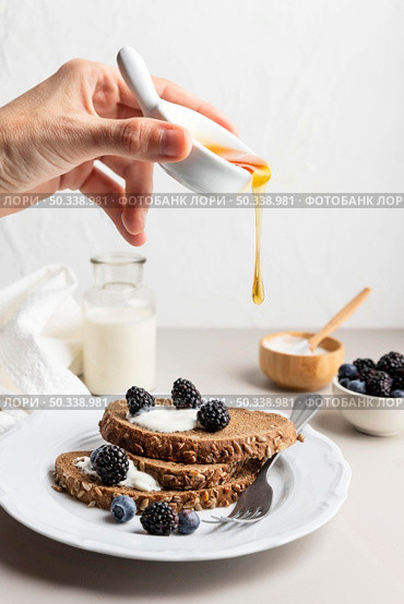 hand pouring honey toast with blueberries. Стоковое фото, агентство Ingram Publishing / Фотобанк Лори