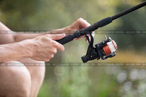 hands fisherman keep spinning rod. Стоковое фото, агентство Ingram Publishing / Фотобанк Лори