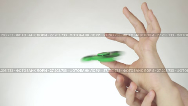 Hands of a teenage girl spin a green fidget spinner on white background stock footage video. Стоковое видео, видеограф Юлия Машкова / Фотобанк Лори