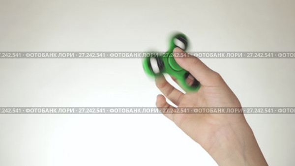 Hands of a teenage girl spin a green fidget spinner on white background stock footage video. Стоковое видео, видеограф Юлия Машкова / Фотобанк Лори
