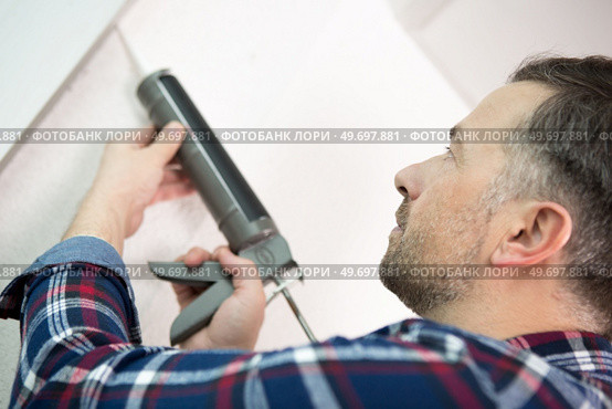 handyman applying sealant with a gun. Стоковое фото, агентство Ingram Publishing / Фотобанк Лори