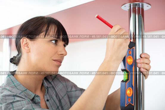 handywoman holding a level ruler on a table. Стоковое фото, агентство Ingram Publishing / Фотобанк Лори