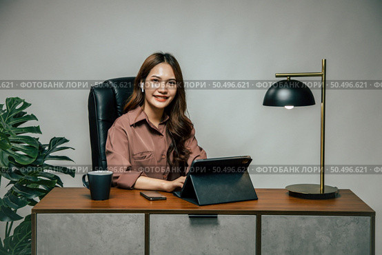 Happily Young asian woman with new normal, she Stay at home and works from home on digital tablet and use smartphone during self-isolation and quarantine covid-19 coronavirus outbreak. Стоковое фото, агентство Ingram Publishing / Фотобанк Лори