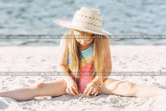 Happy cute smiling little girl in straw hat has fun on the sand on a beach in a swimsuit. Summer concept. Стоковое фото, фотограф Ирина Михайличенко / Фотобанк Лори
