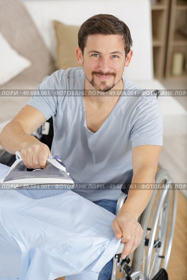 happy disabled man on wheelchair ironing clothing. Стоковое фото, агентство Ingram Publishing / Фотобанк Лори