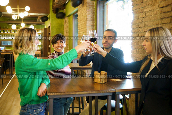 Happy diverse group of friends clinking glasses of alcohol during party in weekend in pub. Man and women proposing toast during party. Стоковое фото, агентство Ingram Publishing / Фотобанк Лори