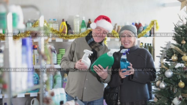 Happy elderly couple choosing detergent and window cleaning spray in supermarket before celebrating Christmas. Стоковое видео, видеограф Яков Филимонов / Фотобанк Лори