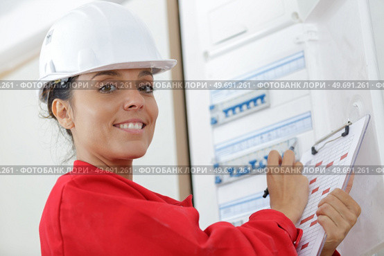 happy female builder inspecting fuse board. Стоковое фото, агентство Ingram Publishing / Фотобанк Лори