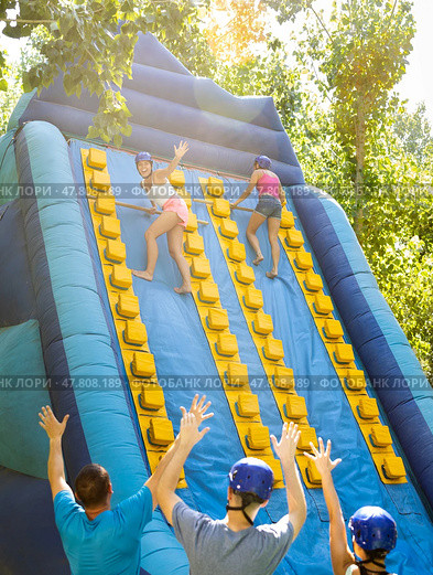 Happy girl competing in climbing with wood poles on inflatable slide. Стоковое фото, фотограф Яков Филимонов / Фотобанк Лори