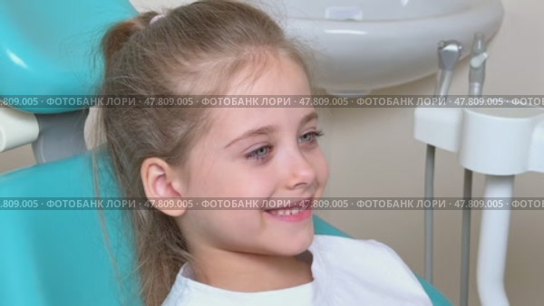 Happy little girl having dentist's appointment in modern clinic. Patient, adorable smiling child sitting in dentist's chair during appointment in pediatric dentistry clinic. Slow motion footage. Стоковое видео, видеограф Ирина Михайличенко / Фотобанк Лори