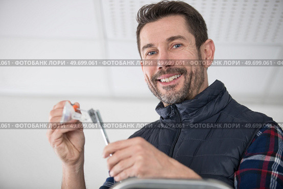 happy man on ladder attaching lamp. Стоковое фото, агентство Ingram Publishing / Фотобанк Лори