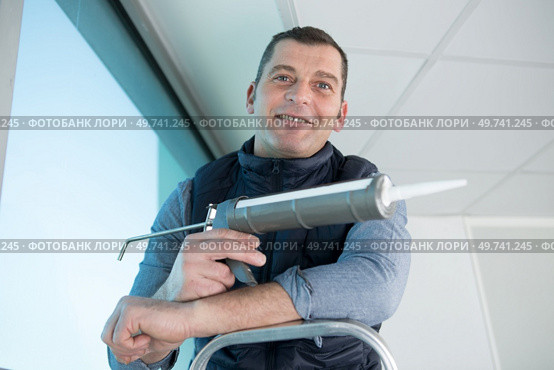happy man with silicone sealant and caulking gun in hand. Стоковое фото, агентство Ingram Publishing / Фотобанк Лори