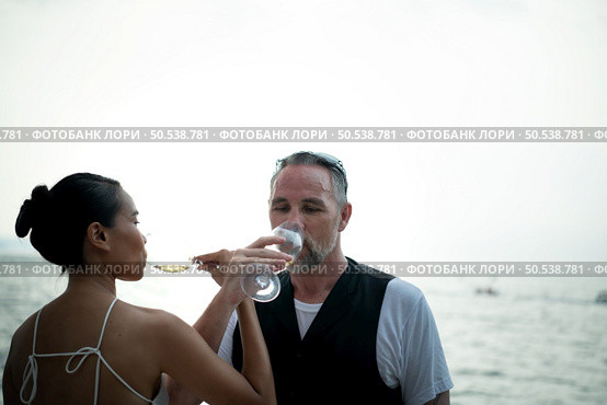Happy moments of interracial couples on a yacht The couple had their honeymoon at one of Asia’s most beautiful seas. Стоковое фото, агентство Ingram Publishing / Фотобанк Лори