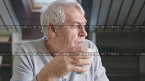 Happy senior man having a coffee break and thinking at home. Face of an old man feeling nostalgic, drink tea during retirement. Elderly man thinking, decision with wellness and calm. Morning routine. Стоковое видео, видеограф Марина Демидюк / Фотобанк Лори