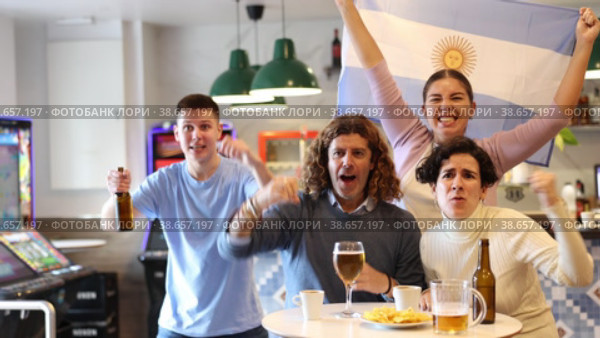 Happy sports supporters with flag of Argentina, rejoicing winning game with beer and snacks in pub. Стоковое видео, видеограф Яков Филимонов / Фотобанк Лори