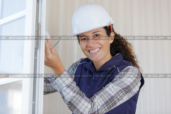 happy woman mounts the tilt and turn stopper on window. Стоковое фото, агентство Ingram Publishing / Фотобанк Лори