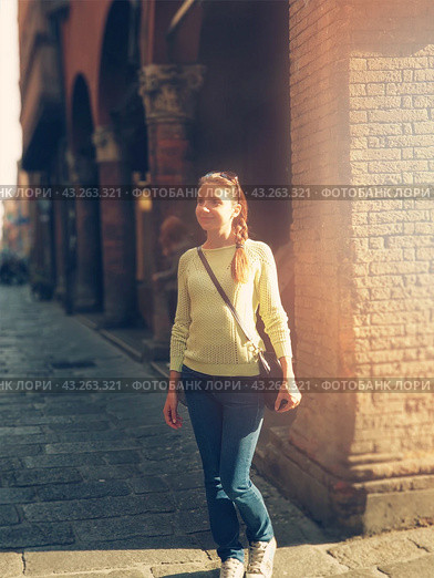 Happy woman portrait walking on the old Bologna street. Smiling girl in yellow sweater walking to the University in morning sun lights. Teenager portrait outdoors. Стоковое фото, фотограф Константин Григорьев / Фотобанк Лори